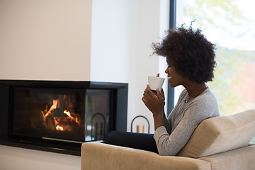 Image showing black woman drinking coffee in front of fireplace