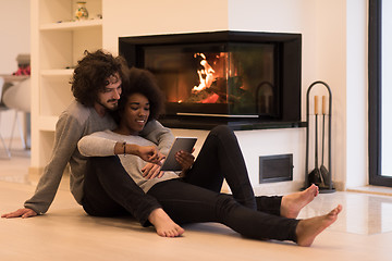 Image showing multiethnic couple using tablet computer on the floor