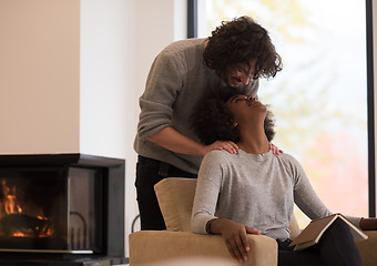 Image showing multiethnic couple hugging in front of fireplace