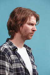 Image showing The serious business man standing and looking at camera against blue background.