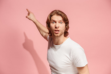 Image showing Beautiful male half-length portrait isolated on pink studio backgroud. The young emotional surprised man