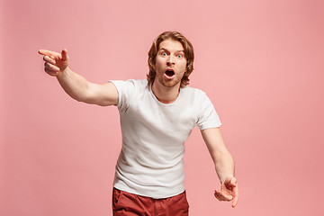 Image showing Beautiful male half-length portrait isolated on pink studio backgroud. The young emotional surprised man