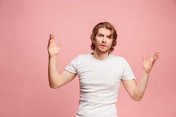 Image showing Beautiful male half-length portrait isolated on pink studio backgroud. The young emotional surprised man