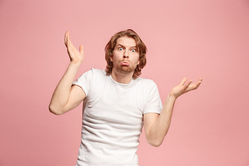 Image showing Beautiful man looking suprised and bewildered isolated on pink