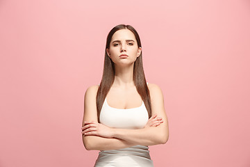 Image showing The serious business woman standing and looking at camera against pink background.