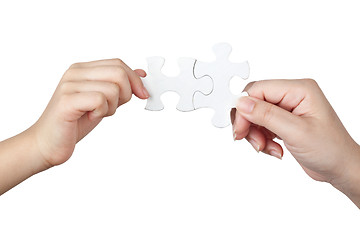 Image showing Female and child hand holding jigsaw puzzle pieces