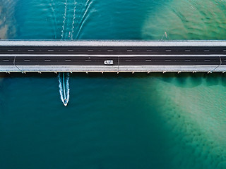 Image showing Car crosses bridge as speed boat travels under it. Aerial view