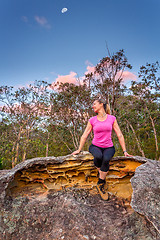 Image showing Happy woman sitting on a rock with moon shining above