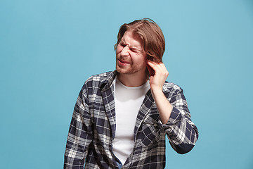 Image showing The Ear ache. The sad man with headache or pain on a blue studio background.