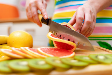 Image showing Women\'s hands Housewives cut with a knife fresh grapefruit on th