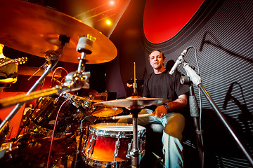 Image showing Drummer playing on drum set on stage.