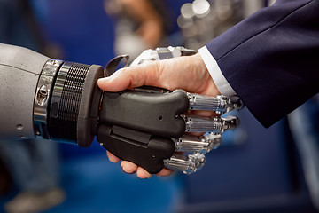 Image showing Hand of a businessman shaking hands with a Android robot.