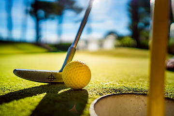 Image showing Mini Golf yellow ball with a bat near the hole at sunset