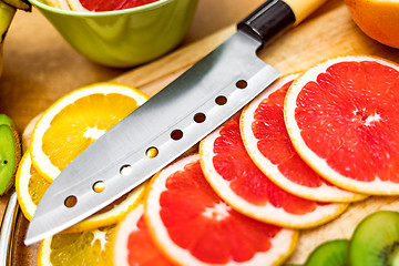 Image showing Sharp kitchen knife on cutting Board next to sliced grapefruit a