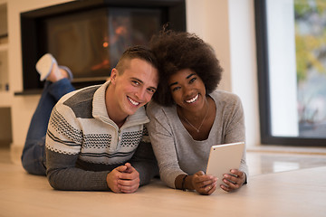 Image showing multiethnic couple using tablet computer on the floor