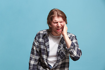 Image showing The Ear ache. The sad man with headache or pain on a blue studio background.