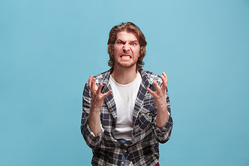 Image showing Portrait of an angry man looking at camera isolated on a blue background