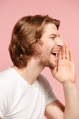 Image showing Isolated on pink young casual man shouting at studio