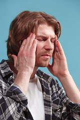 Image showing man having headache. Isolated over blue background.