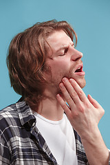 Image showing The Ear ache. The sad man with headache or pain on a blue studio background.