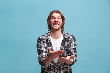 Image showing male half-length portrait isolated on blue studio backgroud. The young emotional surprised man