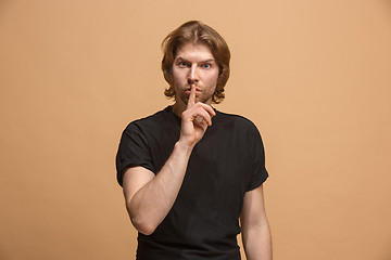 Image showing The young man whispering a secret behind her hand over pastel background