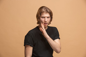 Image showing The young man whispering a secret behind her hand over pastel background