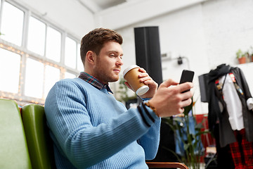 Image showing man with smartphone and coffee at clothing store