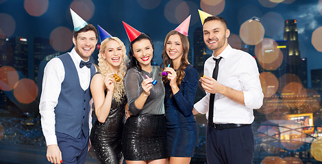 Image showing happy friends with party blowers having fun