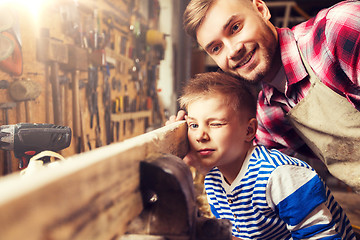 Image showing father and little son with wood plank at workshop