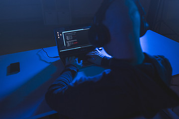 Image showing hacker with coding on laptop computer in dark room