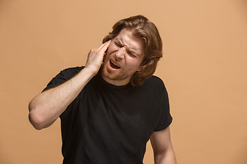 Image showing The Ear ache. The sad man with headache or pain on a pastel studio background.