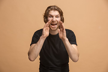 Image showing Isolated on pastel young casual man shouting at studio