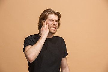 Image showing The Ear ache. The sad man with headache or pain on a pastel studio background.