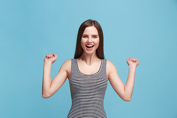 Image showing The happy woman standing and smiling against blue background.