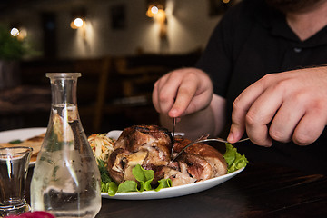 Image showing Man eats tasty dish of pork shank