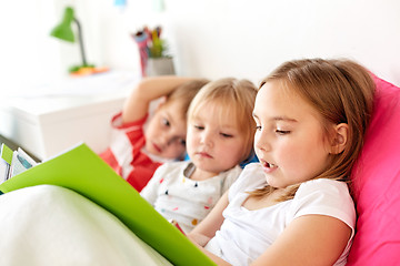 Image showing little kids reading book in bed at home