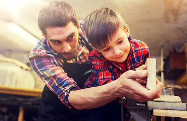 Image showing father and little son with wood plank at workshop