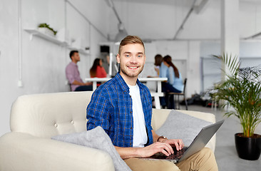 Image showing smiling man with laptop working at office