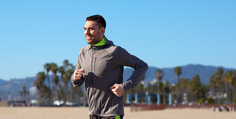 Image showing happy young man running over venice beach