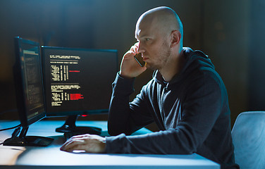 Image showing hacker with program on computer calling on cell