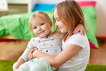 Image showing happy little girls or sisters hugging at home