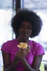 Image showing woman with afro hairstyle eating tasty pizza slice