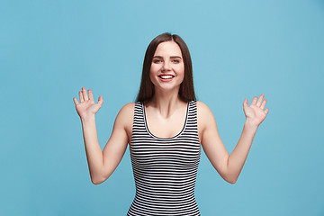 Image showing The happy woman standing and smiling against blue background.