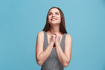 Image showing The happy woman standing and smiling against blue background.