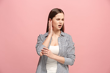 Image showing The Ear ache. The sad woman with headache or pain on a pink studio background.