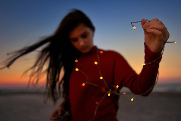 Image showing Teen girl with lights on beach