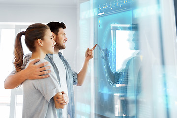 Image showing happy couple looking at futuristic virtual screen