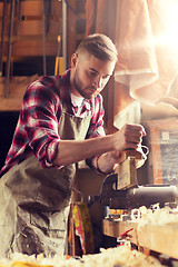 Image showing carpenter working with plane and wood at workshop