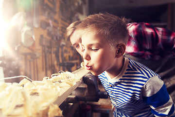 Image showing father and little son with wood plank at workshop